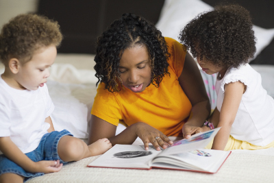 mom reading book to two children
